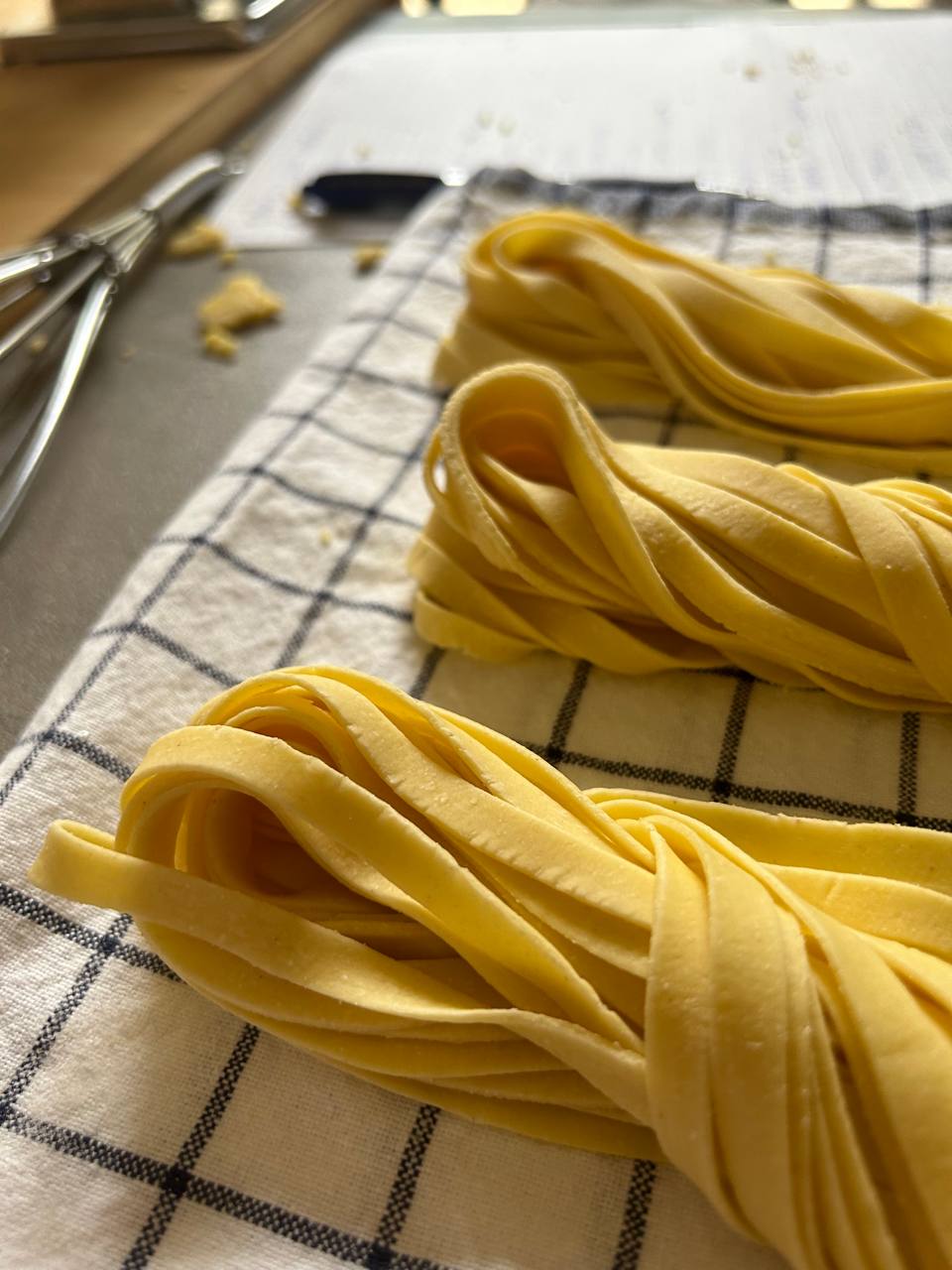 Nidi di tagliatelle fresche all'uovo su un canovaccio a quadri