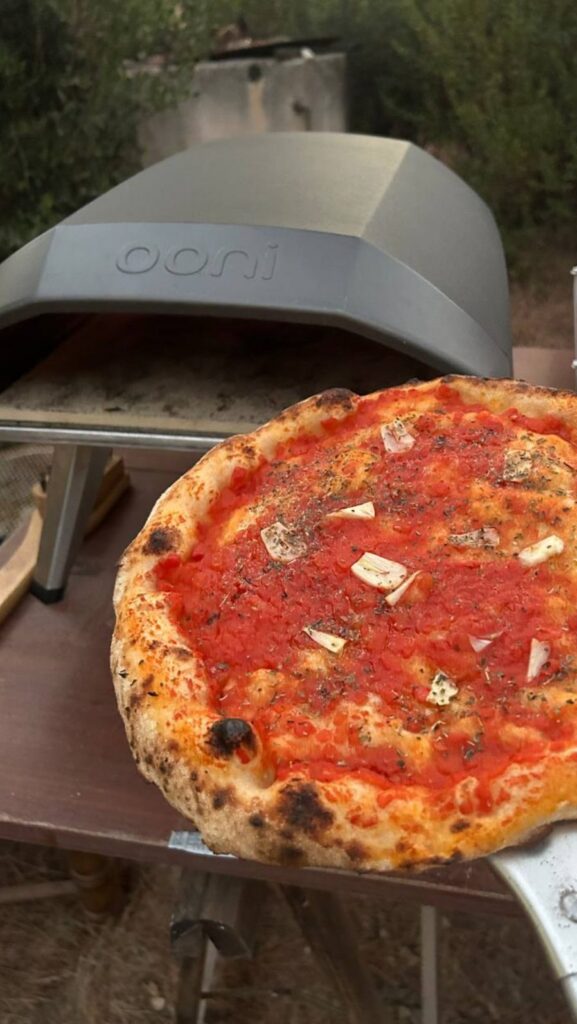 Pizza marinara appena sfornata davanti al forno portatile