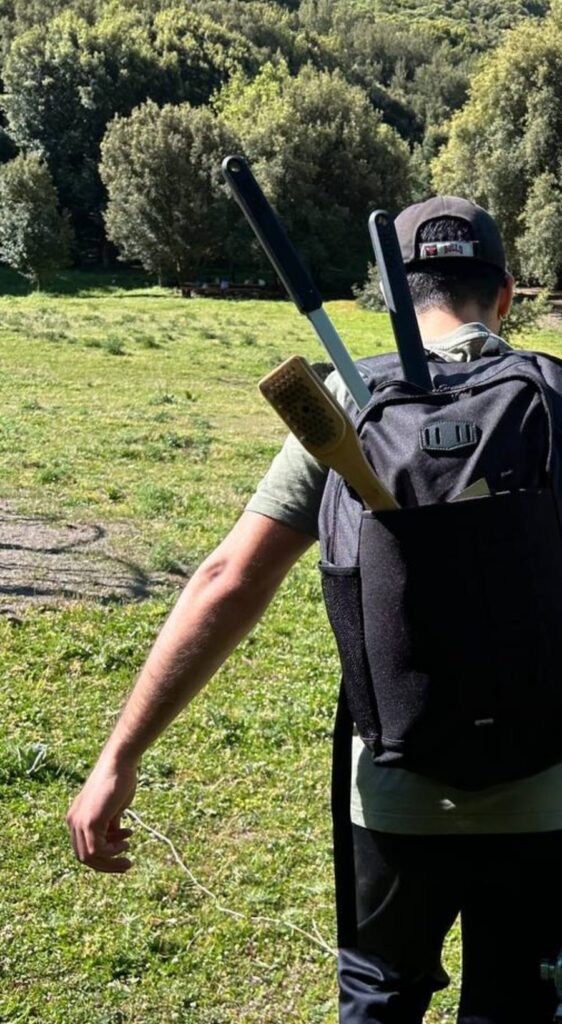Alessio di spalle con lo zaino e le pale da pizza, in viaggio verso una lezione a domicilio